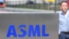 一名员工走过世界最大半导体制造机器供应商、位于费尔德霍芬的荷兰阿斯麦公司（ASML）总部的标识。（法新社2018 年4月17日）