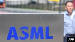 一名員工走過世界最大半導體製造機器供應商、位於費爾德霍芬的荷蘭阿斯麥公司（ASML）總部的標識。（法新社2018 年4月17日）