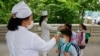 2020年6月3日，北韓平壤一所小學學生在進入學校前接受體溫測量。