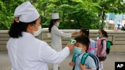 FILE - Kim Song Ju Primary school students have their temperatures checked before entering the school in Pyongyang, North Korea on June 3, 2020.