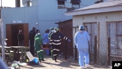 Petugas membawa keluar jenazah dari klub malam di East London, Afrika, Selatan, pada 26 Juni 2022. Polisi masih menginvestigasi kematian 20 orang di sebuah klub malam di East London yang meninggal secara misterius. (Foto: AP)