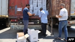 FILE - Customs officials inspect a convoy of humanitarian aid after it crossed into Syria from Turkey through the Bab al-Hawa border crossing, July 8, 2022.