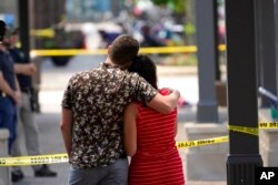 Brooke and Matt Strauss, who were married Sunday, look toward the scene of the mass shooting in downtown Highland Park, Illinois, a Chicago suburb, after leaving their wedding bouquets near the scene of Monday's mass shooting, July 5, 2022.