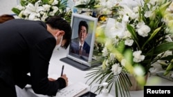 Seorang pelayat di depan foto mendiang mantan Perdana Menteri Jepang Shinzo Abe, yang tertembak saat berkampanye untuk pemilihan parlemen, di Tokyo, Jepang, 11 Juli 2022 (Foto: REUTERS/Issei Kato)