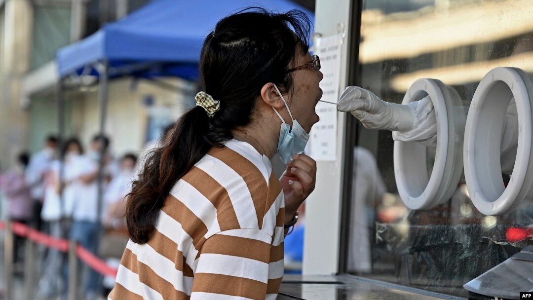 Seorang petugas kesehatan mengambil sampel swab dari seorang perempuan untuk diuji COVID-19 di Beijing, 6 Juli 2022.