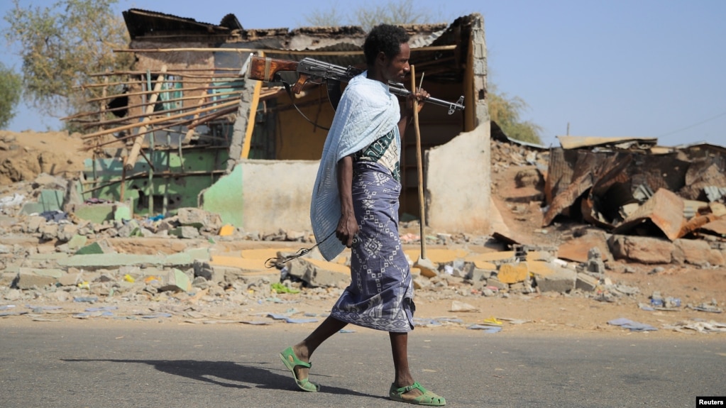 FILE - An Afari militia member walks next to a house destroyed in the fight between the Ethiopian National Defence Forces and the Tigray People's Liberation Front forces in Kasagita town, Afar region, Ethiopia, February 25, 2022. 