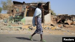 FILE - An Afari militia member walks next to a house destroyed in the fight between the Ethiopian National Defence Forces and the Tigray People's Liberation Front forces in Kasagita town, Afar region, Ethiopia, February 25, 2022. 