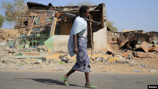 FILE - An Afari militia member walks next to a house destroyed in the fight between the Ethiopian National Defence Forces and the Tigray People's Liberation Front forces in Kasagita town, Afar region, Ethiopia, February 25, 2022.