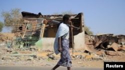 FILE - An Afari militia member walks next to a house destroyed in the fight between the Ethiopian National Defense Forces and the Tigray People's Liberation Front forces in Kasagita town, Afar region, Ethiopia. Taken 2.25.2022