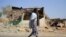 FILE - An Afari militia member walks next to a house destroyed in the fight between the Ethiopian National Defence Forces and the Tigray People's Liberation Front forces in Kasagita town, Afar region, Ethiopia, February 25, 2022. 