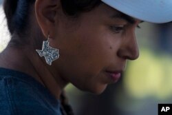 Ana Hernandez, a kindergarten teacher from Dilley, Texas, wears a Texas-shaped earring to show her support for the community.  (AP Photo/Jae C. Hong)