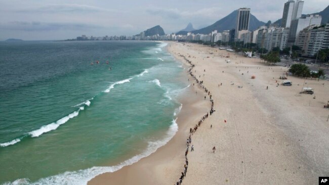 FILE - People create a line along Copacabana beach for a symbolic group hug with the sea on World Oceans Day in Rio de Janeiro, Brazil, June 8, 2022.