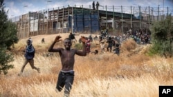 FILE - Migrants run on Spanish soil after crossing the fences separating the Spanish enclave of Melilla from Morocco in Melilla, Spain, on June 24, 2022. Critics decry the lack of officials held to account for the force of the response by authorities. 