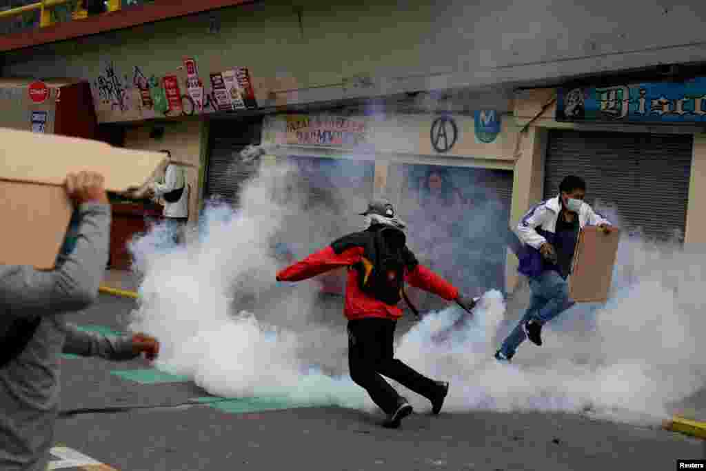 Un manifestante sostiene un bote de gas lacrimógeno durante un enfrentamiento con personal de seguridad.