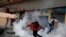 Un manifestante sostiene un bote de gas lacrimógeno durante un enfrentamiento con personal de seguridad.