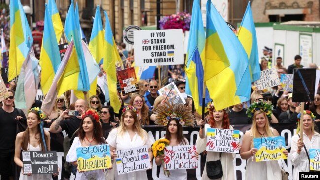People hold Ukrainian flags and signs in support of Ukraine, as they take part in the 2022 Pride Parade in London, July 2, 2022.