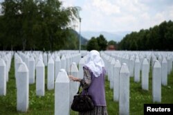 Seorang perempuan Muslim Bosnia menyentuh batu nisan di Srebrenica Genocide Memorial di Potocari, Bosnia dan Herzegovina, 8 Juni 2021. (Foto: REUTERS/Dado Ruvic)