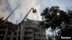 A rescue worker sprays water on an apartment building destroyed in a missile strike, amid Russia's invasion of Ukraine, in Kyiv, June 26, 2022.