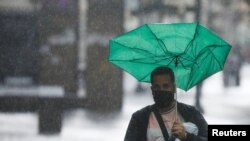 Una persona se protege de la lluvia causada por el potencial ciclón tropical dos, que según el Centro Nacional de Huracanes de EEUU probablemente se convertirá en la tormenta tropical Bonnie, a su paso por el Caribe, en Caracas, Venezuela, el 29 de junio de 2022. REUTERS/Leonardo Fernández Viloria