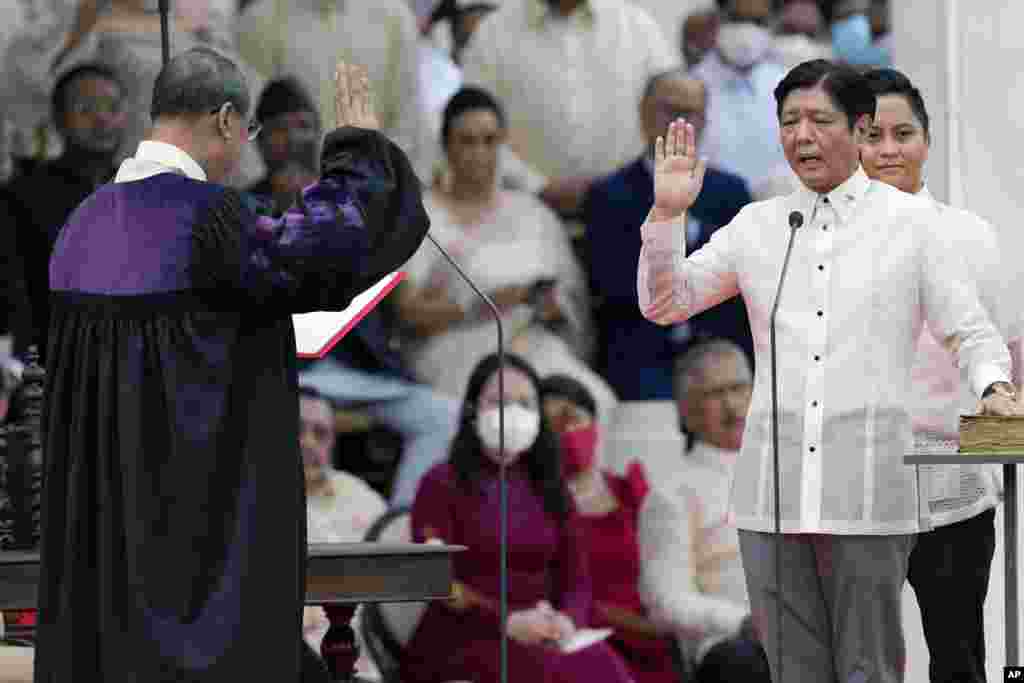 Presiden terpilih Ferdinand &quot;Bongbong&quot; Marcos Jr., kanan, dilantik oleh Ketua Mahkamah Agung Alexander Gesmundo saat upacara peresmian di Museum Nasional di Manila, Filipina (30/6). (Foto: AP)&nbsp;