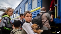Хлопчик тримає свого собаку під час евакуації з зони війни. Родина сідає в евакуаційний потяг у Покровську, східна Україна, 25 червня 2022 року. (AP Photo/Efrem Lukatsky)