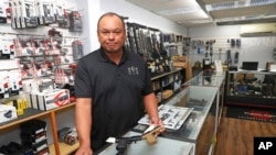 Tom Tomimbang, managing partner at the 808 Gun Club, shows off several small handguns inside his shop, June, 23, 2022 in Honolulu.