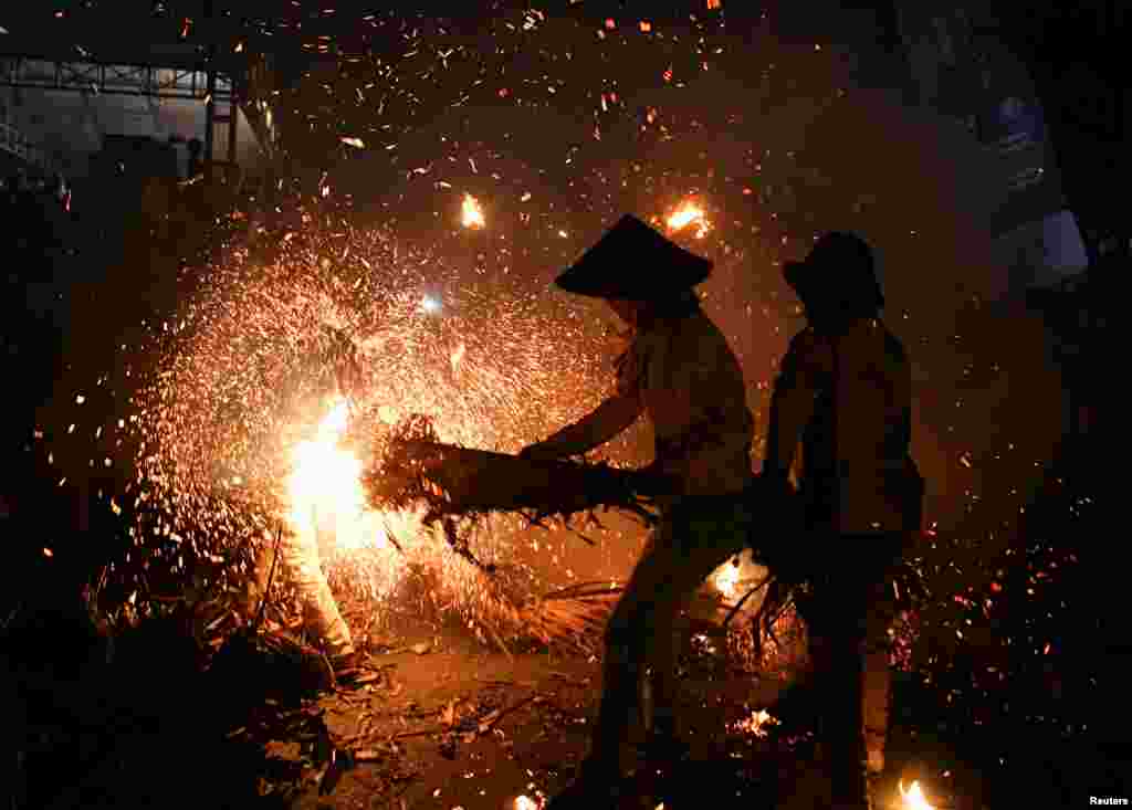 Young people play with sparks and flames from coconuts and banana leaves during a torch battle following a yearly traditional event to express thanks for the harvest and reject reinforcements in Tahunan Village, Jepara, Central Java province, Indonesia, June 20, 2022.
