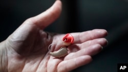 Chelle Wyatt holds her hearing aid Friday, April 15, 2022, in Salt Lake City. (AP Photo/Rick Bowmer)