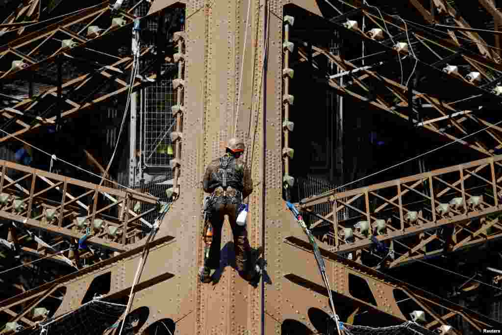 A worker is seen on the Eiffel tower during the 20th campaign of painting and stripping of the Eiffel tower in Paris, France.