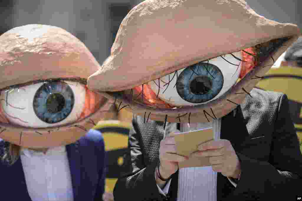 Activists wearing masks of large eyeballs attend a protest against planned updates of the country&#39;s national security laws, after a draft was leaked to the media earlier this month, in Bucharest, Romania.