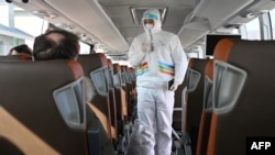 A member of staff wearing a hazmat suit greets media on a bus as they arrive in the Zhangjiakou Zone, east of Beijing ahead of the Beijing 2022 Winter Olympics, on Jan. 31, 2022.