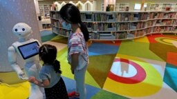 Anak-anak menggunakan robot untuk mendapatkan bantuan di perpustakaan Mohammed Bin Rashid (MBRL) yang baru dibuka di Dubai pada 16 Juni 2022. Desainnya menggabungkan teknologi dan kecerdasan buatan. (Foto: AFP)