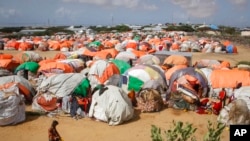Los somalíes que huyeron de las zonas afectadas por la sequía caminan junto a un grupo de refugios improvisados en un campamento para desplazados en las afueras de Mogadiscio, Somalia, el 4 de junio de 2022.