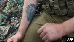 A photograph taken on June 18, 2022, shows a close-up view of a Ukrainian serviceman's tattoo as he mans an entrenched position on the front line near Avdiivka, Donetsk region amid the Russian invasion of Ukraine.