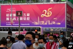 People walk past a billboard featuring the celebration of the 25th anniversary of Hong Kong handover to China, in Hong Kong, June 17, 2022.