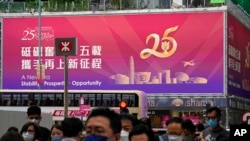 People walk past a billboard featuring the celebration of the 25th anniversary of Hong Kong handover to China, in Hong Kong, June 17, 2022.