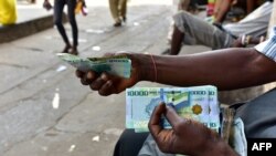 ARCHIVES - Des changeurs de monnaie tiennent des billets sur un trottoir à Freetown, en Sierra Leone, le 30 mars 2018.