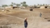 Seorang perempuan berjalan untuk mengambil air dari pompa tangan terdekat dengan pendingin air di kepalanya, saatgelombang panas, di pinggiran Jacobabad, Pakistan, 16 Mei 2022. (REUTERS/Akhtar Soomro)