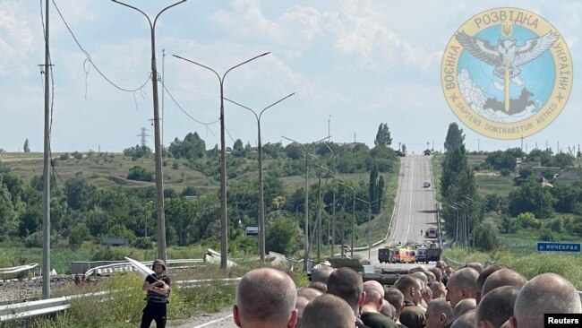 Seorang pria yang memegang bendera putih mengawasi proses pertukaran tawanan perang antara Rusia dan Ukraina di wilayah Zaporizhzhia, dalam foto yang dirilis pada 29 Juni 2022. (Foto: Ukraine's Military Intelligence/Handout via Reuters)