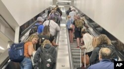 Los viajeros ascienden por una escalera mecánica hasta una explanada en el Aeropuerto Internacional Hartsfield-Atlanta el jueves, 30 de junio de 2022 en Atlanta. (Foto AP/Jay Reeves)