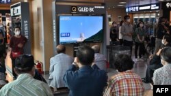 People watch a television screen showing a live footage of South Korea's homegrown space rocket Nuri, at a railway station in Seoul, June 21, 2022,