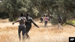 FILE: Migrants run on Spanish soil after crossing the fences separating the Spanish enclave of Melilla from Morocco in Melilla, Spain, 6.24.2022