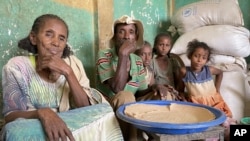 FILE - Tesfay sits with his wife and grandchildren, who have been displaced, as they receive food assistance for the first time in eight months from the World Food Program (WFP), in Mehameday, in Ethiopia's Tigray region, May 28, 2022. 