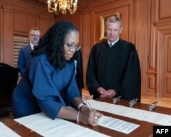 In this handout image released by the U.S. Supreme Court, Chief Justice John Robert, watches as Justice Ketanji Brown Jackson signs the Oaths of Office in the Justices' Conference Room at the Supreme Court in Washington, D.C., on June 30, 2022.