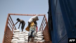Petugas memindahkan karung gandum ke kereta barang di stasiun kereta api Chawa Pail di Khanna, negara bagian Punjab, 19 Mei 2022. (Sajjad HUSSAIN/AFP)