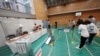 Staff members of a local election administration commission gather before voting began for the upper house election at a polling station July 10, 2022, in Tokyo.