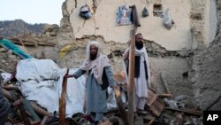 Afghan men sift through debris after an earthquake, in Gayan village, Paktika province, Afghanistan, June 23, 2022.