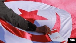 FILE - A man places a copy of the Tunisian constitution atop a Tunisian national flag during a demonstration called for by Tunisia's Islamist-inspired Ennahdha party against President Kais Saied's recent decrees, in the capital Tunis, Feb. 13, 2022.