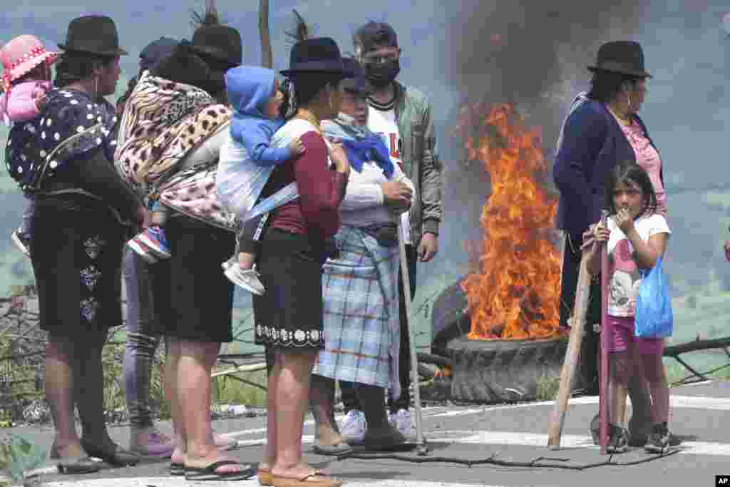 Mujeres se paran junto a una barricada en llamas mientras bloquean una carretera durante una manifestación nacional contra el gobierno de Guillermo Lasso convocada principalmente por organizaciones indígenas, en Santa Rosa, Ecuador, el martes 14 de junio de 2022. (Foto AP/Dolores Ochoa )