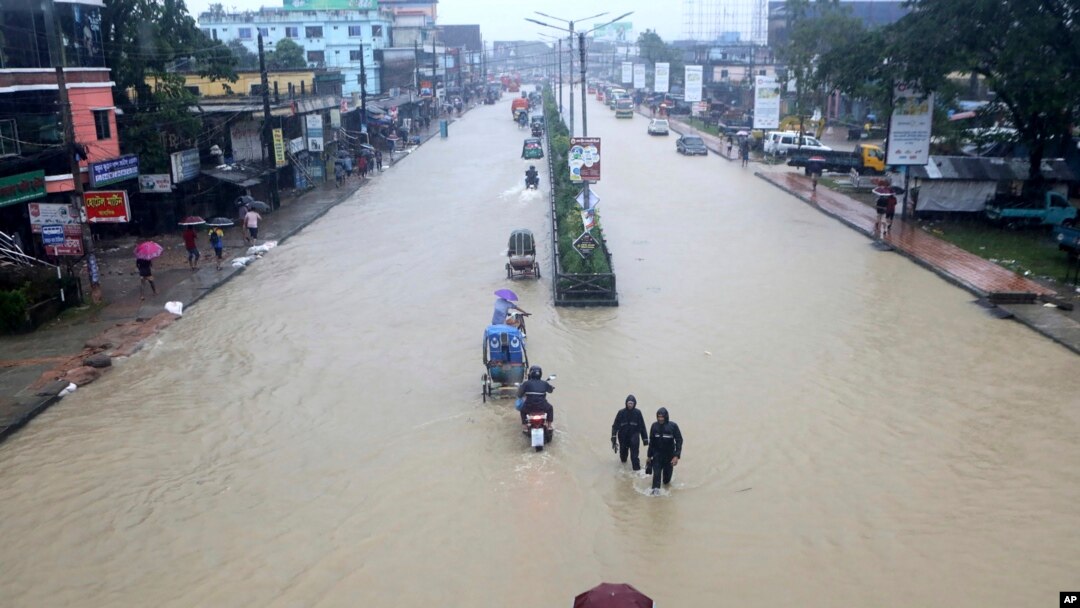 Warga menyeberangi jalanan yang tergenang banjir di Sylhet, Bangladesh, Minggu 18 Juni 2022. 